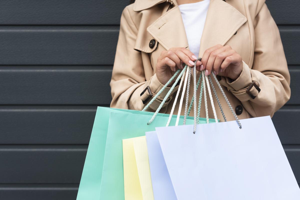 een vrouw houdt verschillende winkeltasjes vast