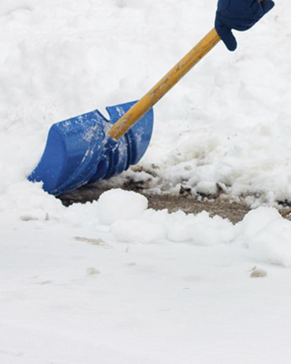 een sneeuwruimer ruimt een dikke laag sneeuw met een schop