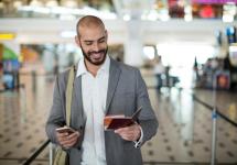 Een glimlachende man in de luchthaven kijkt naar zijn paspoort