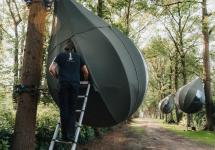 een kampeerder opent een van de boompittenten in domein Franciscanessen