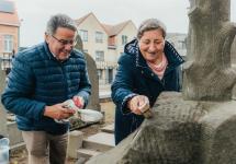 twee vrijwilligers reinigen een oud graf op het kerkhof van Wuustwezel-centrum