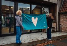 medewerkers van de bibliotheek tonen de Koestervlag, die tijdens de Koesterweek wordt uitgehangen aan de bib van Wuustwezel